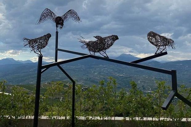 α μαύρα πουλιά από σύρμα σε τεθλασμένες δοκούς με φόντο τις πλαγιές της Ζήριας